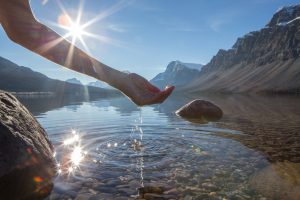 Human hand cupped to catch the fresh water from lake